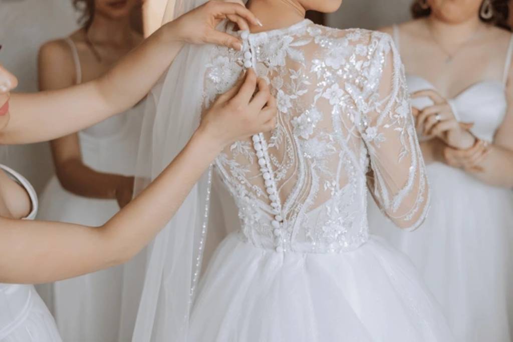 Bride examining intricate lace details on wedding gown in boutique mirror